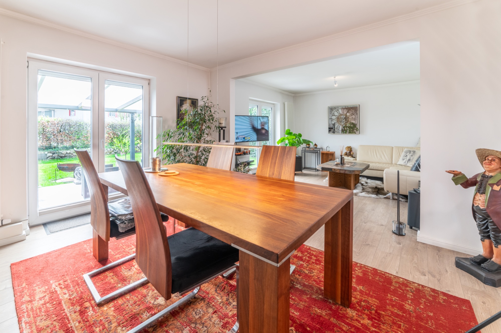 Modernes Esszimmer mit Holztisch, Stühlen und Blick auf den Garten. Stilvolle Einrichtung.