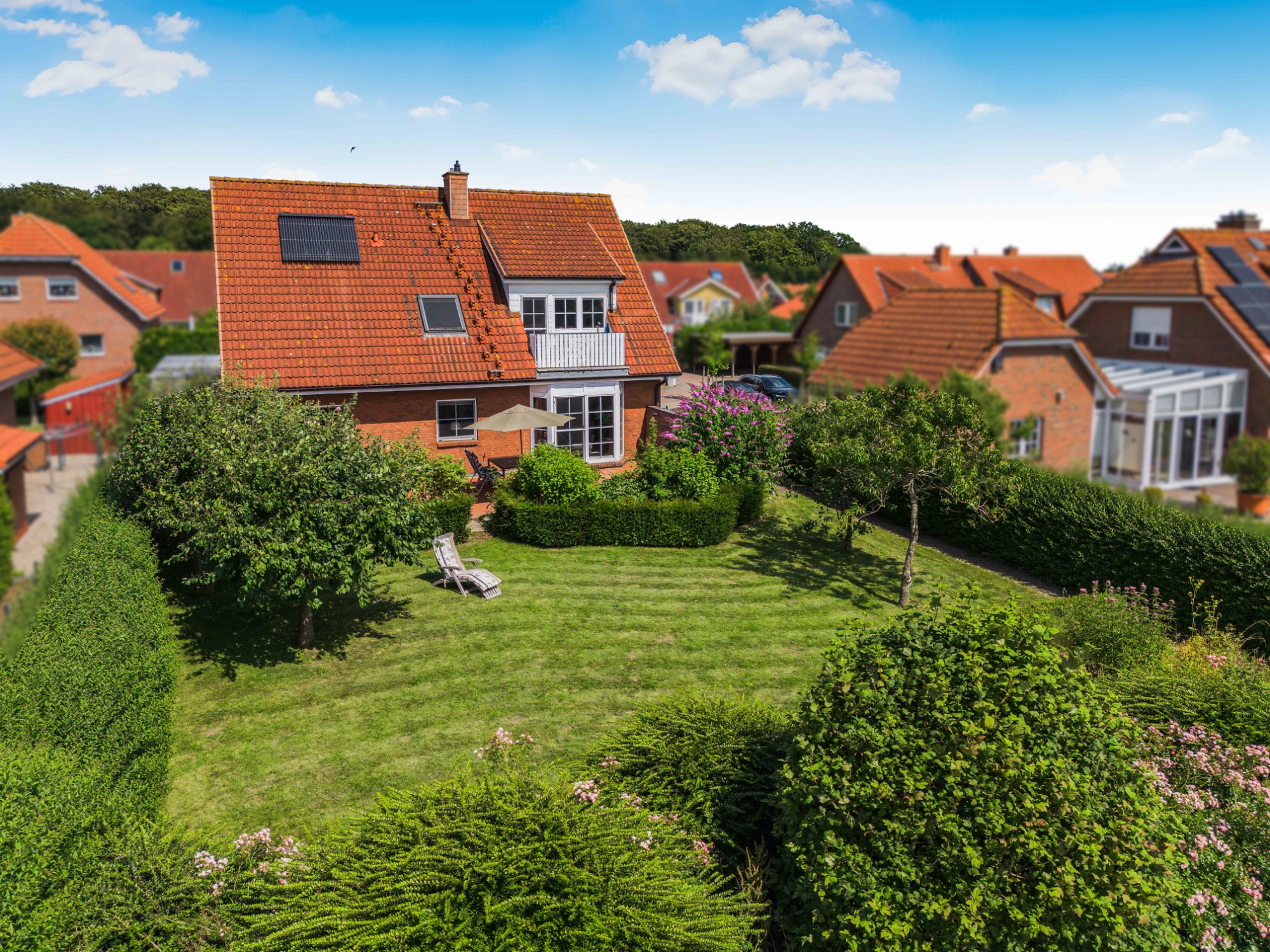 Modernes Haus mit rotem Dach und gepflegtem Garten in einer ruhigen Wohngegend.