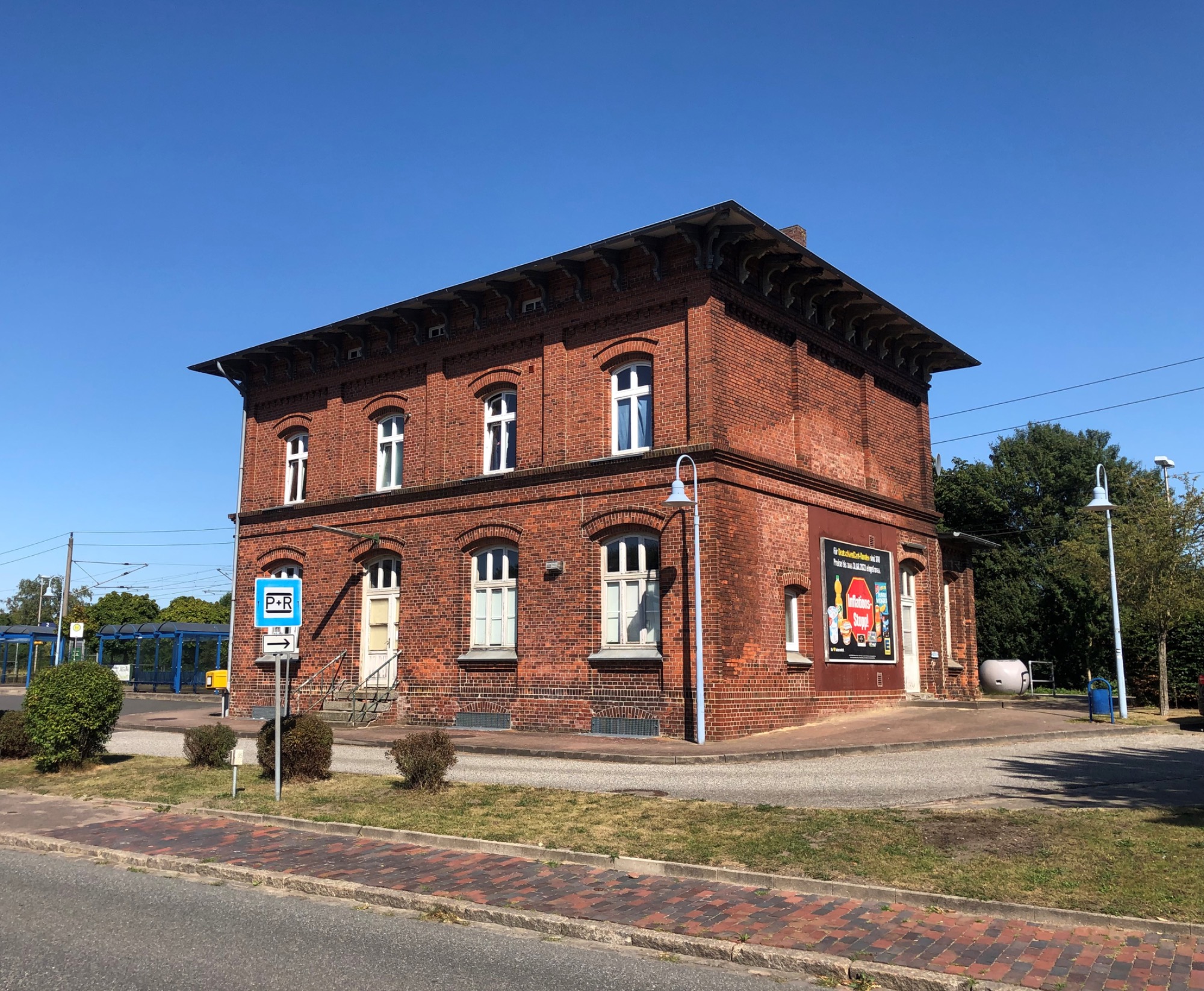 Rotes Backsteingebäude mit mehreren Fenstern und einem klaren blauen Himmel.