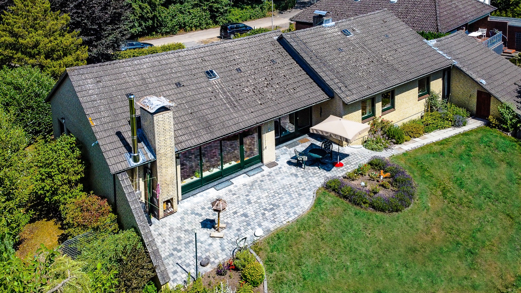 Ein modernes Einfamilienhaus mit Garten und Steinweg, umgeben von Bäumen.